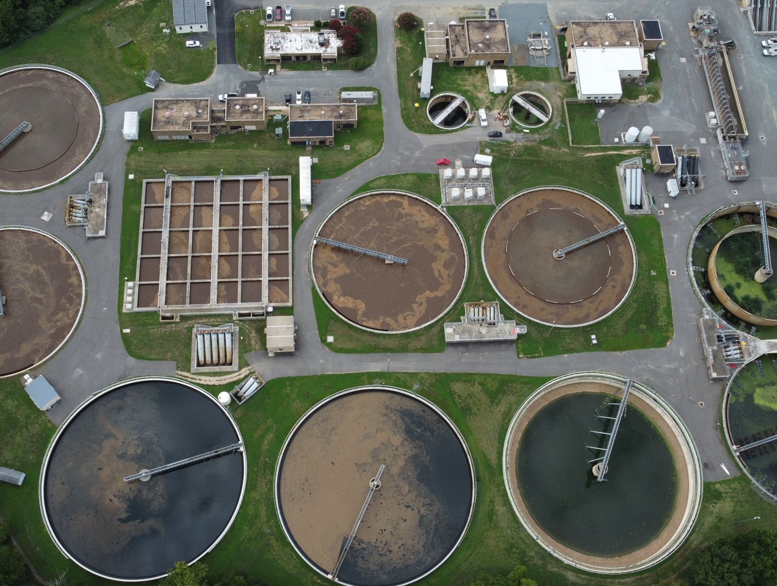Aerial view of circular treatment basins and buildings at a wastewater treatment facility